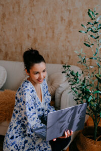 Nő laptopot használ, otthon ül.